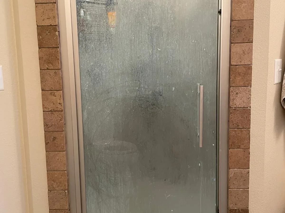 shower glass covered with visible soap and mineral residue before professional house cleaning